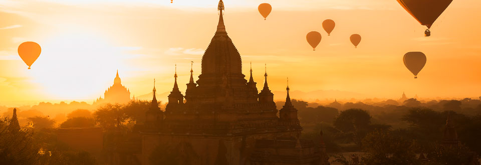 Varmluftballoner over gamle templer i solopgang.