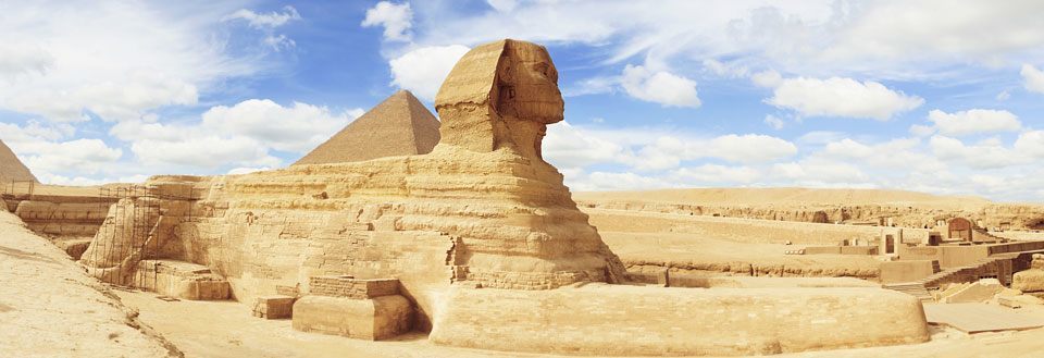 Billede af Sfinksen og pyramiderne i Giza på en solbeskinnet dag med klar blå himmel.