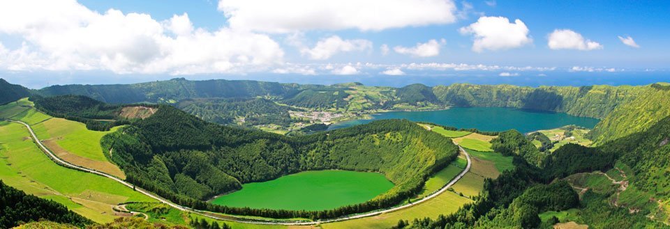 Panoramaudsigt over frodige, grønne vulkanske kratersøer omgivet af skovklædte bakker.