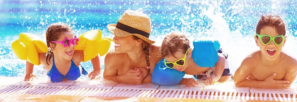 Børn leger i en swimmingpool på en solskinsdag, udstyret med svømmevinger og solbriller.