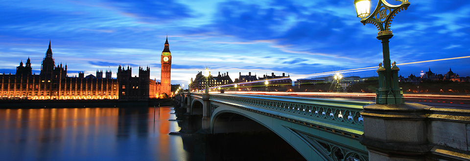 Westminster Bridge og Big Ben ved blå time med lysstræk og oplyst parlament.