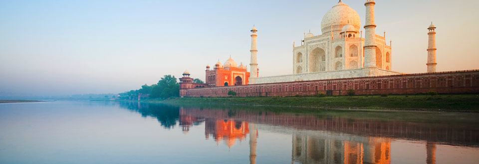 Billedet viser Taj Mahal ved floden Yamuna i aftensolen, spejler sig i vandet.