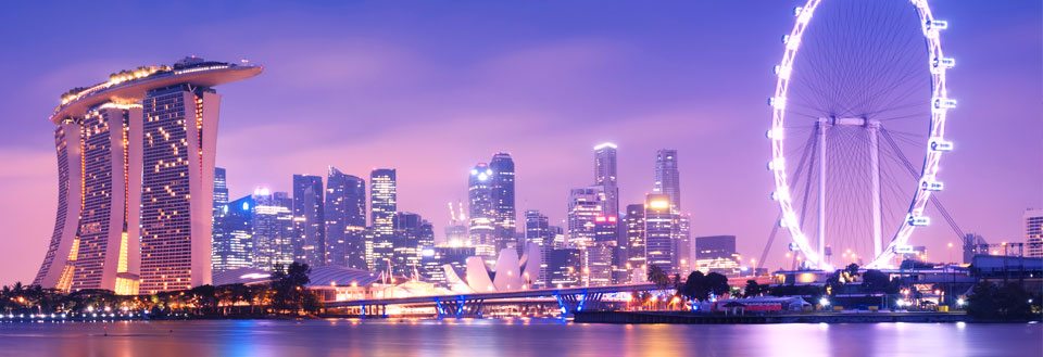 Billedet viser Singapores skyline om aftenen med Marina Bay Sands og et stort pariserhjul.