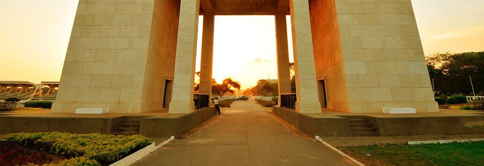 Billedet viser et storslået monument med åbne søjler ved solnedgang, skabende en varm, gylden atmosfære.