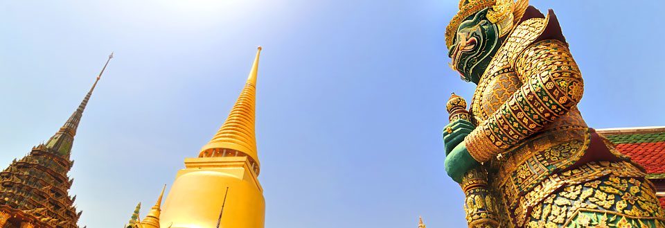 Grand Palace i Bangkok med gyldne spir og en stor, dekoreret statue.