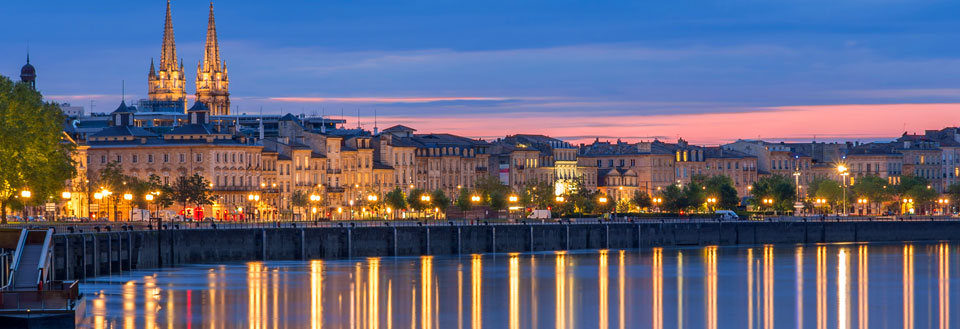 Bordeauxs skyline ved skumring med bygninger reflekteret i vandet.