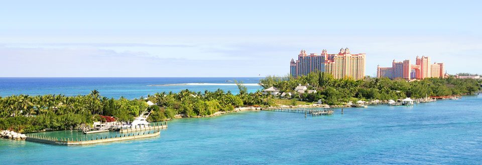 Panoramaudsigt over et tropisk resort med luksuriøse bygninger ved strandkanten under en klar himmel.
