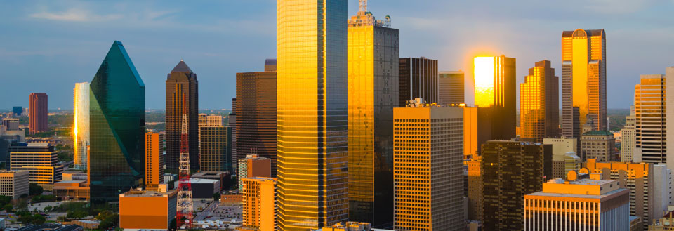 Dallas ved solnedgang med moderne højhuse, der glimter i den aftagende sol.