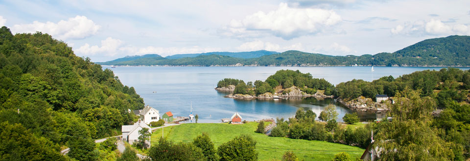 Idyllisk norsk fjord med huse, grønne områder og småøer.