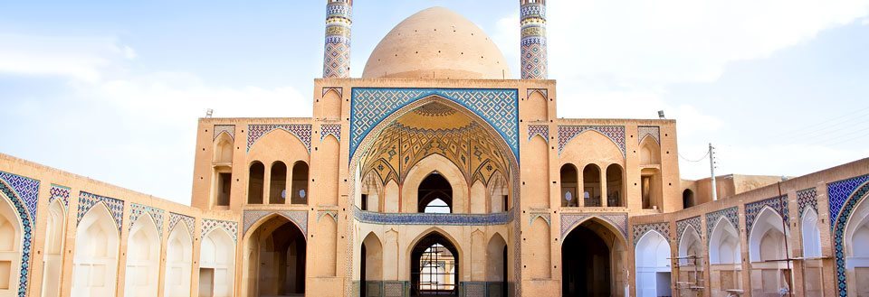 Smuk, gammel moské med imponerende buer og detaljeret flisekunst under en klar blå himmel.
