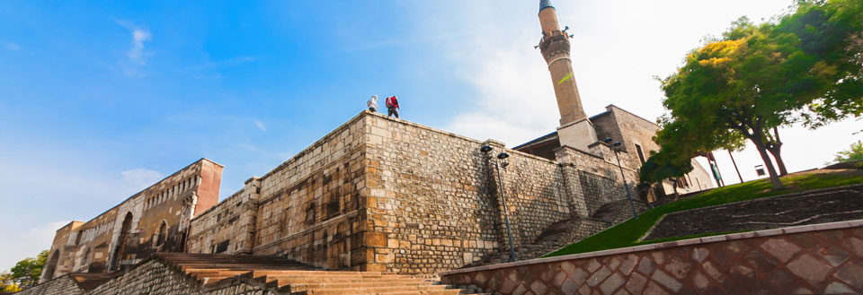 Historisk bygning med en minaret, høje stenmure og personer, der nyder udsigten.