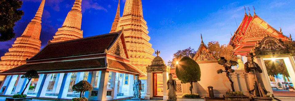 Wat Pho-templet i Bangkok ved skumring med oplyste chedis (stupaer) og smukt dekorerede pavilloner.