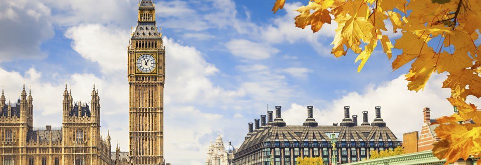 Big Ben og Westminster-paladset i London med gyldne efterårsblade i forgrunden.