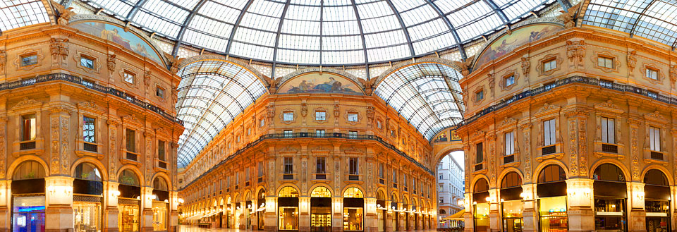 Indvendig panorama af storslået glaskuplet i bygning med elegante buer og butikker.