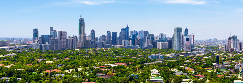 Panoramaudsigt over by med moderne skyskrabere og omkringliggende grønne områder.