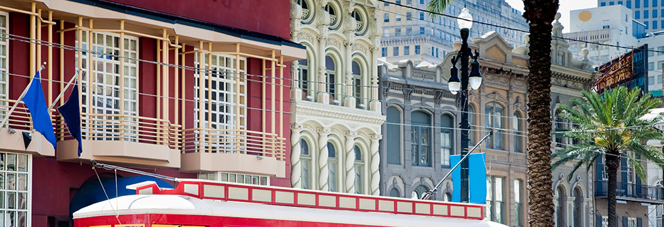 Farverig bygning med balkon prydet af flag i bymiljø med palmer.