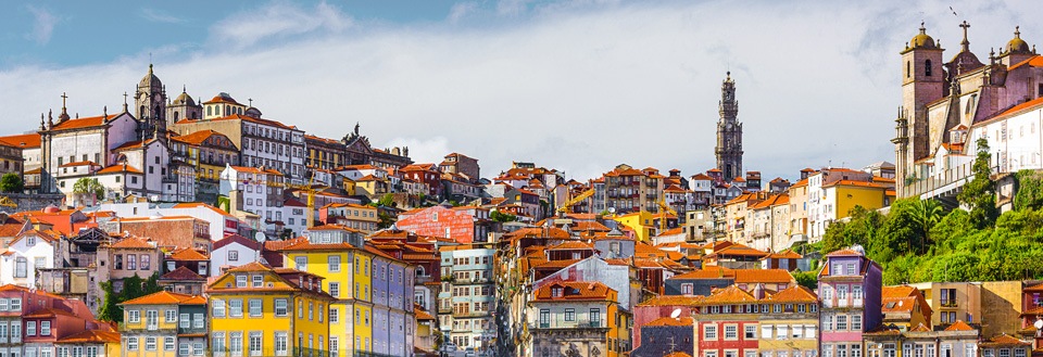 Farverige huse stablet på bakker med Portos historiske bygninger og en klar himmel.