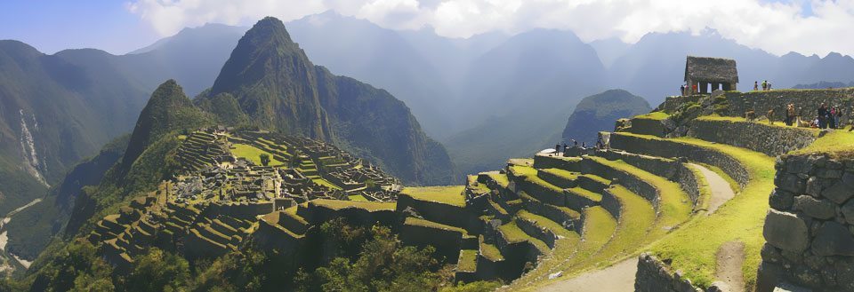 Machu Picchu med terrasseformede marker og neblige bjerge i baggrunden.