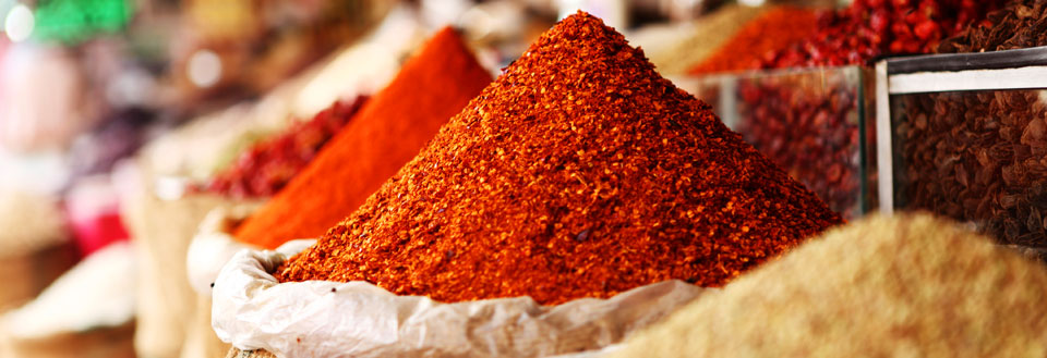 Farverige krydderibjerge på et marked, en blanding af røde og brune nuancer.