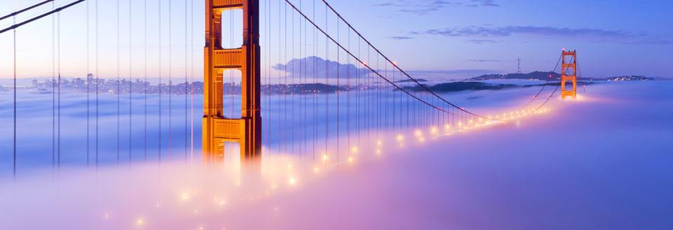 Golden Gate-broen i skumringen, belyst og svævende over en tæt tåge.