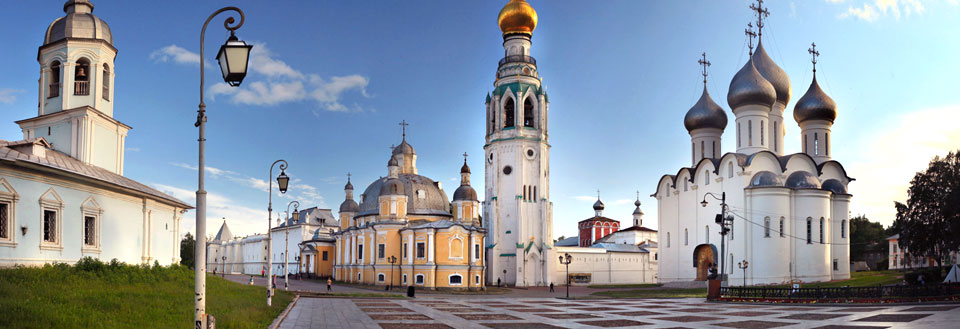 Panoramabillede af russisk kirkelandskab med farverige kupler og tårne under en klar himmel.