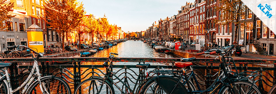 Eftermiddagssol bader kanalhuse og cykler i varmt lys i Amsterdam.