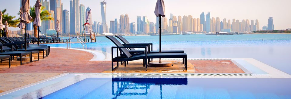 Luksuriøs swimmingpool foran den moderne skyline med imponerende skyskrabere i Dubai.