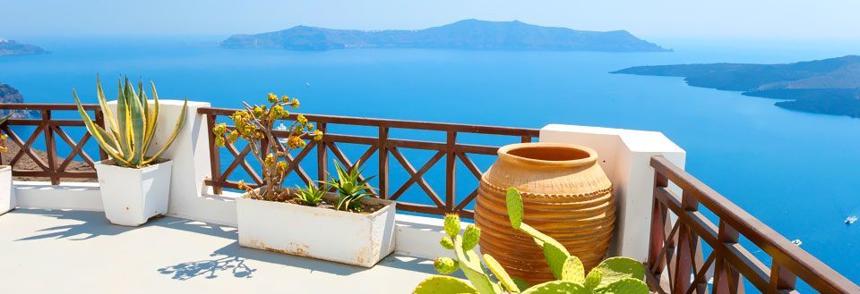 Terrasse med havudsigt og planter i krukker. Blåt vand og himmel, feriestemning.