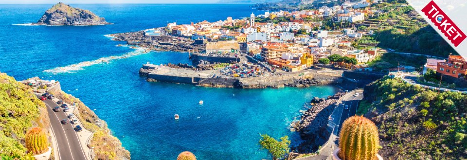 En malerisk kystby med farverige huse, omgivet af klart blåt hav og en frodig kystlinje.