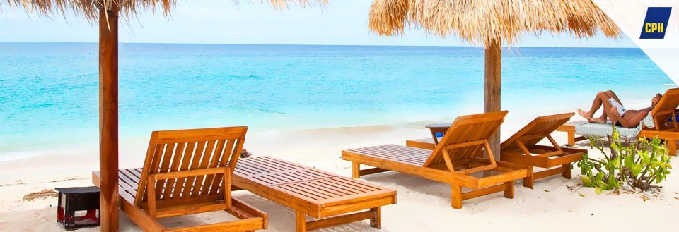 En afslappende strand med træsolstole under en stråparasol ved klart blåt hav.