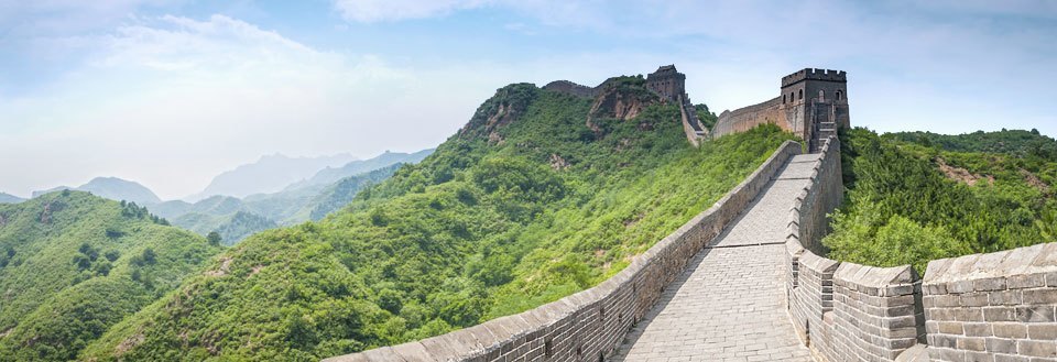 Panorama af Den Kinesiske Mur som buer sig gennem et frodigt landskab.
