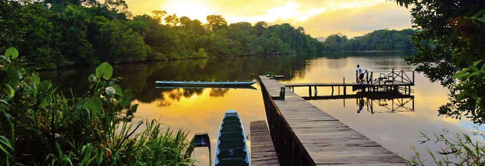 En fredelig morgen ved en sø med en træbro og en person, der nyder udsigten.
