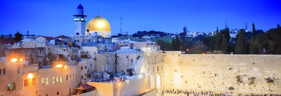 Aftenbillede af Vestermur og Klippemoskeen i Jerusalem, belyste bygninger og mennesker ved muren.