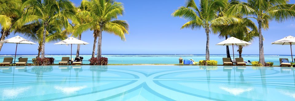 Tropisk feriested med svømmebassin og palmetræer ved en klar, blå himmel.