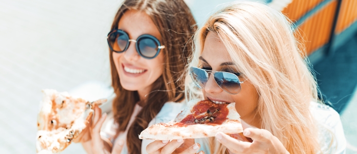 Unge kvinder spise pizza på ferien