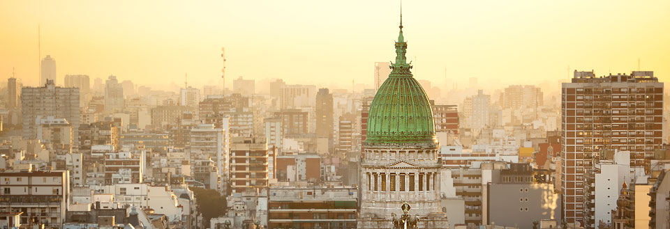 Billede af en Buenos Aires skyline ved solnedgang med en fremtrædende kuppelbygning.