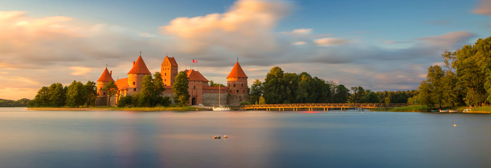 Majestætisk middelalderborg omgivet af vand ved solnedgang.