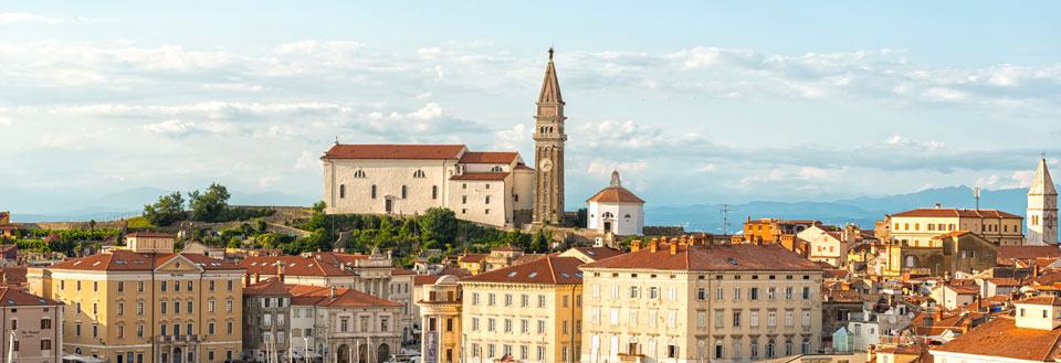 Udsigt over en slovensk by ved solnedgang med historiske bygninger og et klassisk klokketårn.