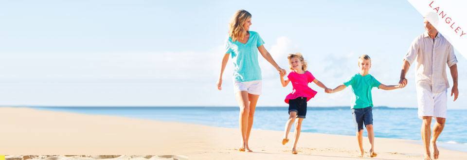 En familie nyder en tur langs stranden med klart blå himmel.