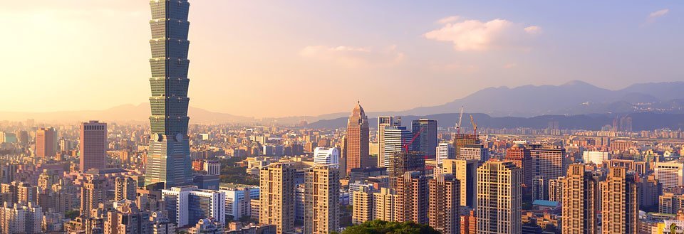 Taipei ved solnedgang med højhuse og en markant skyskraber, der tårner sig op.